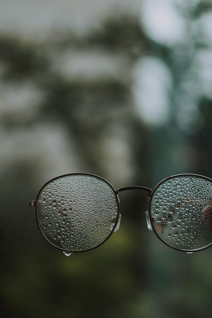Round glasses covered in water droplets focus on condensation and moisture.
